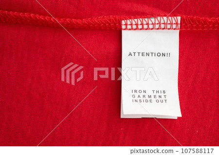 White laundry care washing instructions clothes label on red cotton shirt 107588117