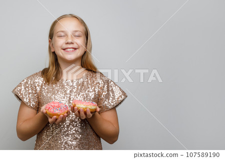 Pretty little girl kid holding two pink donut on white background. Make a wish. Pretty little girl kid holding two pink donut on white background. Make a wish. 107589190