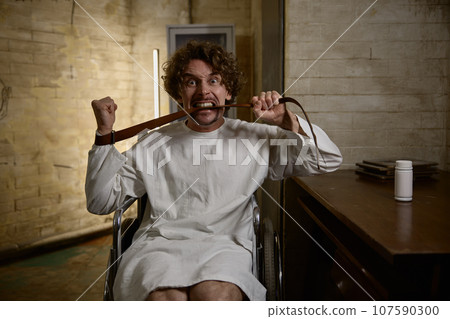 Mad man patient biting leather belt at doctor appointment 107590300