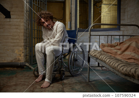Mentally ill patient wearing straitjacket sitting in wheelchair 107590324