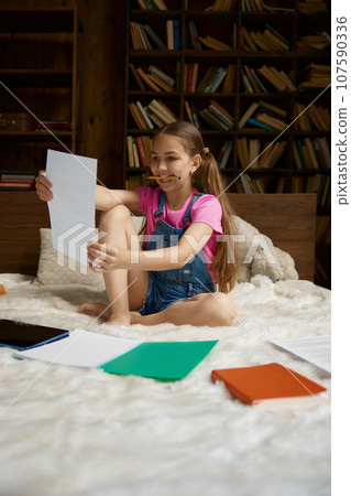 Happy positive schoolgirl studying at home making creative work for art class 107590336