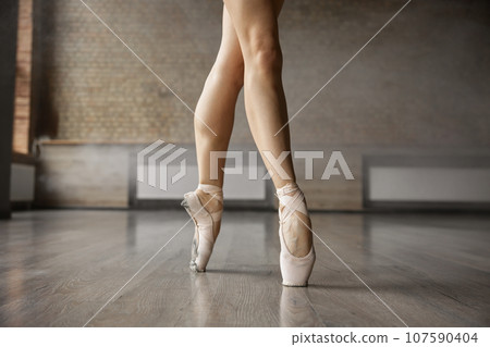 Crossed ballerina legs in pointe shoes closeup shot Crossed ballerina legs in pointe shoes closeup shot 107590404