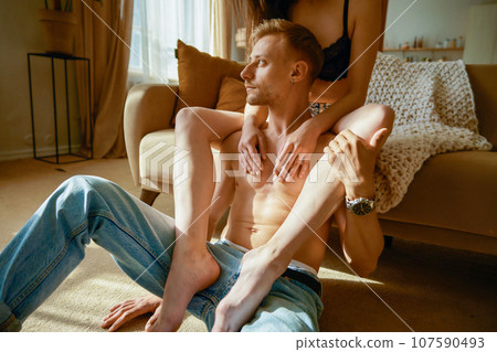 Erotic half dressed couple rest together in home living room Erotic half dressed couple rest together in home living room 107590493