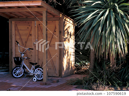 Gardening shed and children's bicycle in the garden Gardening shed and children's bicycle in the garden 107590619