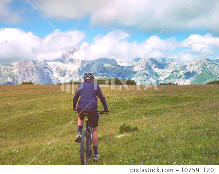 Boy sit on mountain bike and watching from Alps peak Boy sit on mountain bike and watching from Alps peak 107591120