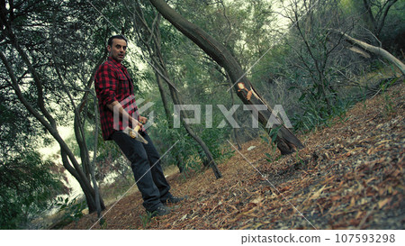 Lumberjack man is cutting a tree trunk in a forest 107593298