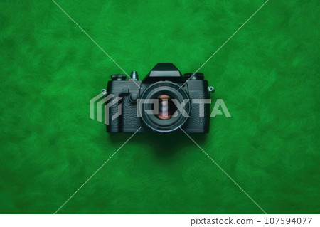 Top View of Sleek Black Camera on Vibrant Green Background 107594077