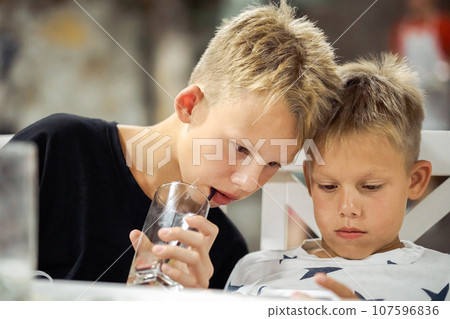 Concentrated boys watch video on mobile phone in restaurant Concentrated boys watch video on mobile phone in restaurant 107596836