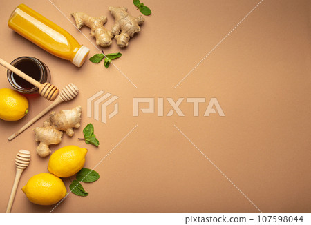 Orange detox drink, lemons, mint, ginger, honey in glass jar, honey wooden dippers top view. Food for immunity stimulation and against flu. Healthy remedies to boost immune system, copy space 107598044