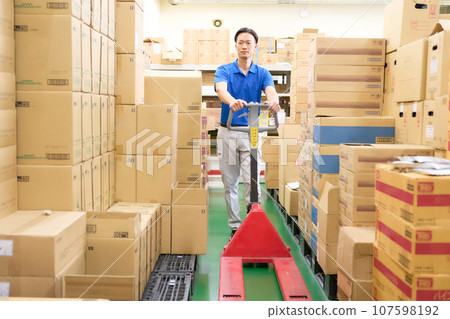 A man working in a warehouse using a hand lift A man working in a warehouse using a hand lift 107598192