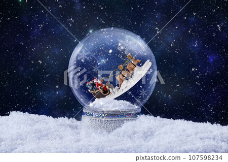 Christmas snow globe with Santa Claus ride on reindeer inside. Christmas greeting card with magic snow globe decoration with snow falling. Christmas background. 107598234