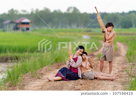 Asian woman look like older sister with traditional cloth sit close to young boy with one stand Asian woman look like older sister with traditional cloth sit close to young boy with one stand 107598419