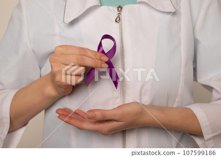 Violet purple ribbon awareness symbolic bow color in doctor's hand for Pancreatic cancer, Hodgkin's lymphoma, epilepsy and Testicular Cancer 107599186