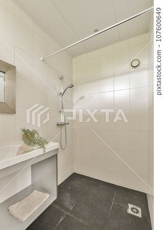 a bathroom with a sink, mirror and shower head mounted on the wall next to it is a flower in a vase a bathroom with a sink, mirror and shower head mounted on the wall next to it is a flower in a vase 107600649