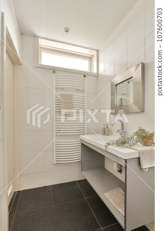 a modern bathroom with black tile flooring and white tiles on the walls, there is a large mirror above the sink 107600703
