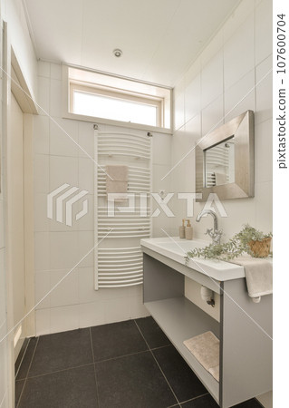 a modern bathroom with black tile flooring and white tiles on the walls, there is a large mirror above the sink 107600704