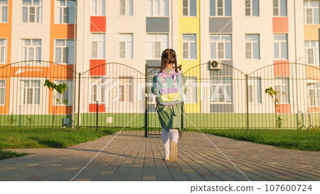 small child with backpack his shoulders goes school lesson. Happy childhood little girl daughter. school bag shoulders small child. education young students. daughter with backpack goes class first 107600724