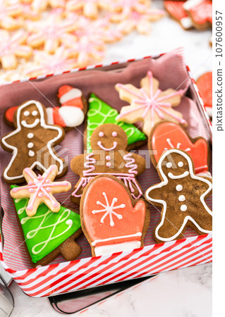 Packaging a homemade variety of fudge and gingerbread cookies for Christmas food gifts into tin boxes. Packaging a homemade variety of fudge and gingerbread cookies for Christmas food gifts into tin boxes. 107600957