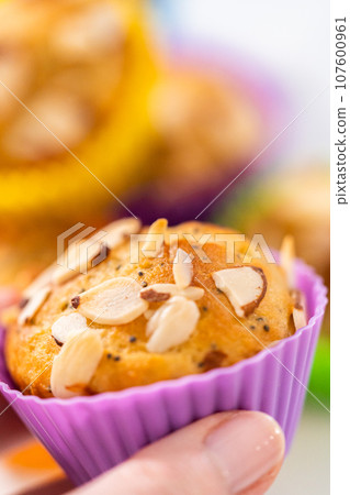 Freshly baked lemon poppy seed muffins garnished with almond slivers on the kitchen counter. 107600961