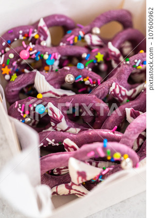 Packaging homemade mermaid pretzel twists into a white paper box. 107600962