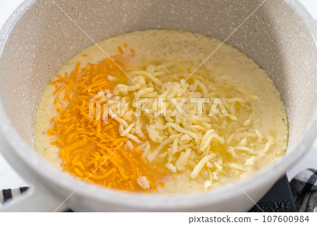 Cooking cheesy sauce in a cooking pot to prepare macaroni and cheese with broccoli. Cooking cheesy sauce in a cooking pot to prepare macaroni and cheese with broccoli. 107600984