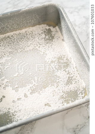 Greasing metal square baking pan to bake sweets. 107601033