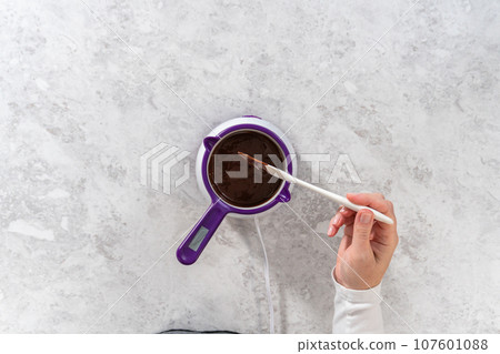 Flat lay. Melting chocolate chips in a candy melting pot to make the chocolate drizzle for banana cookies. 107601088