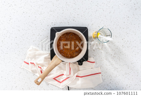 Flat lay. Caramelizing sugar in a saucepan to make caramel cupcake toppers. Flat lay. Caramelizing sugar in a saucepan to make caramel cupcake toppers. 107601111