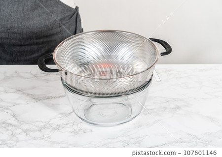 Draining boiled elbows pasta to prepare macaroni and cheese with broccoli. 107601146