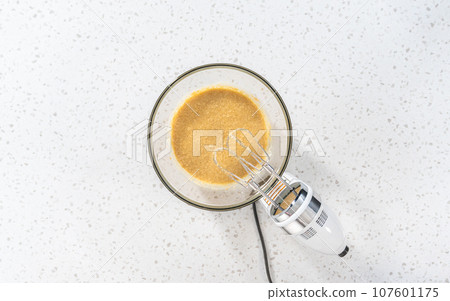Flat lay. Mixing ingredients with a hand mixer in a large mixing bowl to bake dulce de leche cupcakes. Flat lay. Mixing ingredients with a hand mixer in a large mixing bowl to bake dulce de leche cupcakes. 107601175