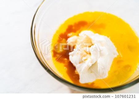 Mixing ingredients in a large glass mixing bowl to bake red velvet bundt cake with cream cheese glaze. 107601231