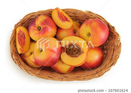 Ripe nectarine fruit with half in a wicker basket isolated on white background with full depth of field. Top view. Flat lay 107601624
