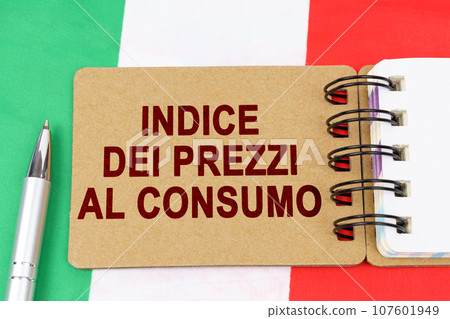 Economy and finance concept. On the flag of Italy lies a pen and a notebook with the inscription - consumer price index. Text in Italian. Economy and finance concept. On the flag of Italy lies a pen and a notebook with the inscription - consumer price index. Text in Italian. 107601949