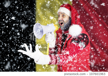 Santa Claus shouts into a bullhorn and shows an aggressive gesture with his hand against the background of the flag of Belgium. Santa Claus shouts into a bullhorn and shows an aggressive gesture with his hand against the background of the flag of Belgium. 107601963