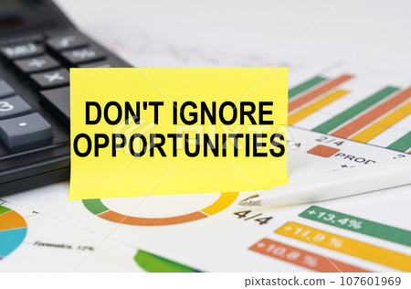 Business concept. On business reports there is a calculator and a sign with the inscription - Don't Ignore Opportunities Business concept. On business reports there is a calculator and a sign with the inscription - Don't Ignore Opportunities 107601969