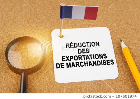 Economy and finance concept. On the table are a magnifying glass, a pencil, the flag of France and a sheet of paper with the inscription - reduction in exports of goods. Text in French. Economy and finance concept. On the table are a magnifying glass, a pencil, the flag of France and a sheet of paper with the inscription - reduction in exports of goods. Text in French. 107601974