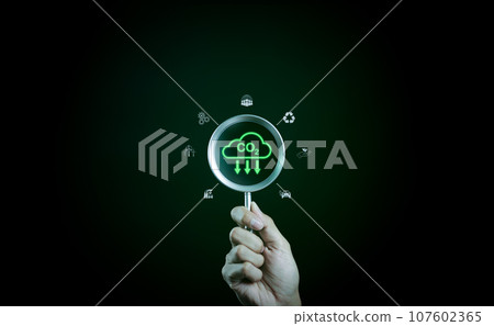 Reduce CO2 emission concept. Hand holding a magnifying glass with environmental icons. Carbon footprint, Sustainable CO2 management, Net Zero, Green business, Renewable energy, Low carbon energy, 107602365