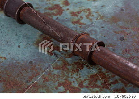 Rusty plumb tube on rusty metal wall 107602580