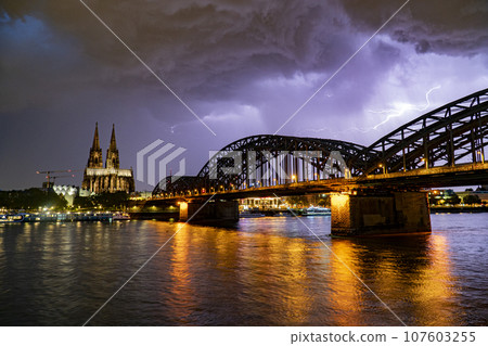 Lightning and dramatic storm clouds over Cologne Cathedral and Hohenzollern Bridge 107603255