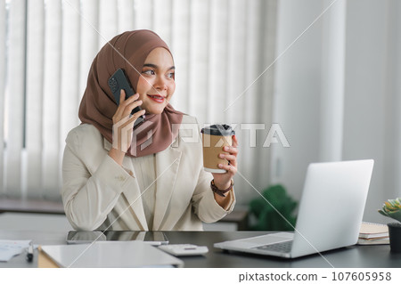 Young muslim millennial businesswoman in brown hijab headscarf working with laptop computer at the modern office. Young muslim millennial businesswoman in brown hijab headscarf working with laptop computer at the modern office. 107605958