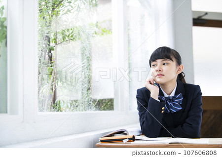 Junior high school girl resting her chin next to the window Junior high school girl resting her chin next to the window 107606808