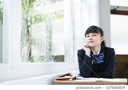 Junior high school girl resting her chin next to the window Junior high school girl resting her chin next to the window 107606809