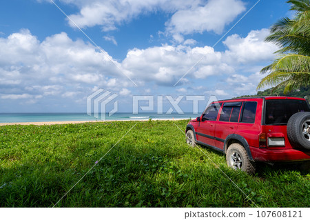 Red SUV 4x4 car on the mountain with Summer sea and blue sky background,Copy space for summer text and travel transportation background. Red SUV 4x4 car on the mountain with Summer sea and blue sky background,Copy space for summer text and travel transportation background. 107608121