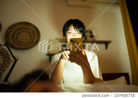 一位女士在半夜看她的智慧型手機。 107608738