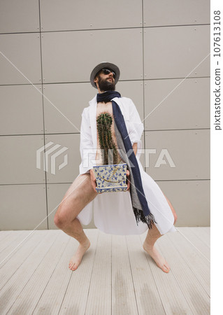 Concept. A man holds a cactus as a symbol of rectal pain. Varicose veins of the lower intestine. Concept. A man holds a cactus as a symbol of rectal pain. Varicose veins of the lower intestine. 107613108