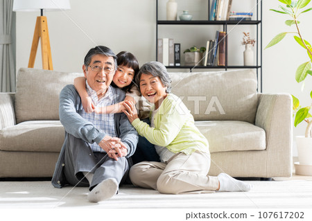 Granddaughter and senior couple relaxing in the living room Granddaughter and senior couple relaxing in the living room 107617202