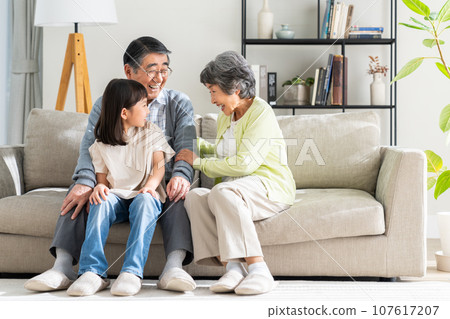 Granddaughter and senior couple relaxing in the living room Granddaughter and senior couple relaxing in the living room 107617207