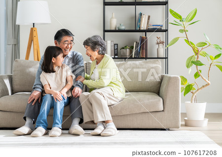 Granddaughter and senior couple relaxing in the living room 107617208