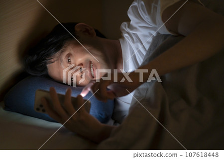男人在床上使用智慧型手機 男人在床上使用智慧型手機 107618448