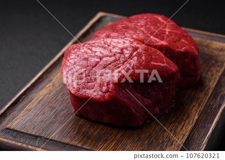 Fresh juicy raw beef medallions with salt and spices 107620321